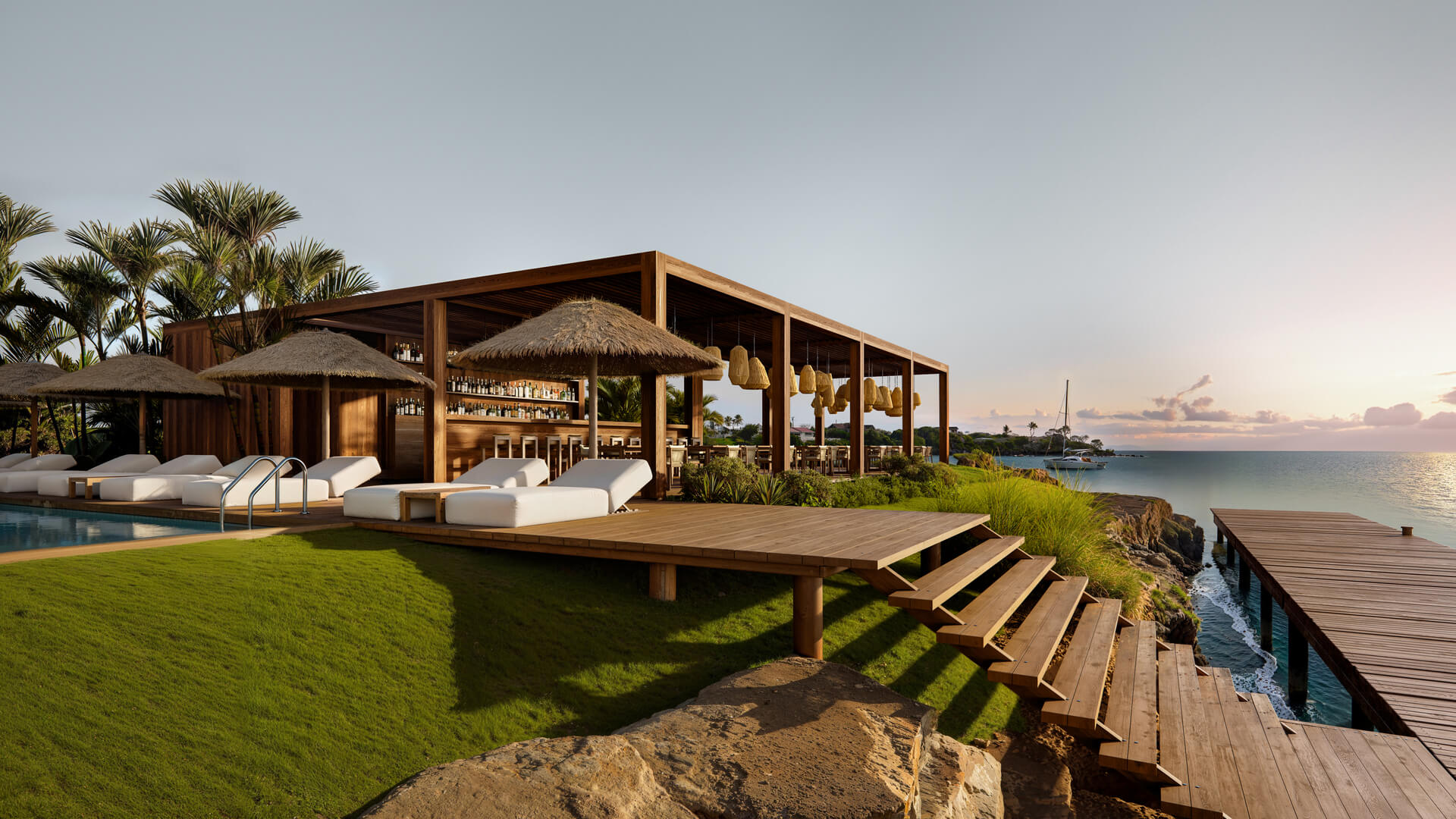 Luxury beachfront bar and pool with wooden deck and steps leading to ocean.