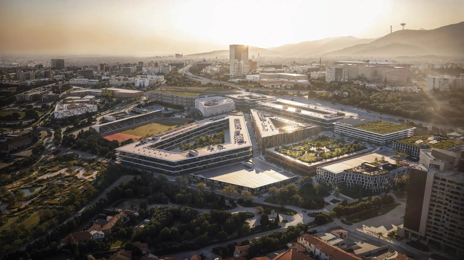 Aerial view of a modern campus at sunset, showcasing green spaces and innovative architecture.